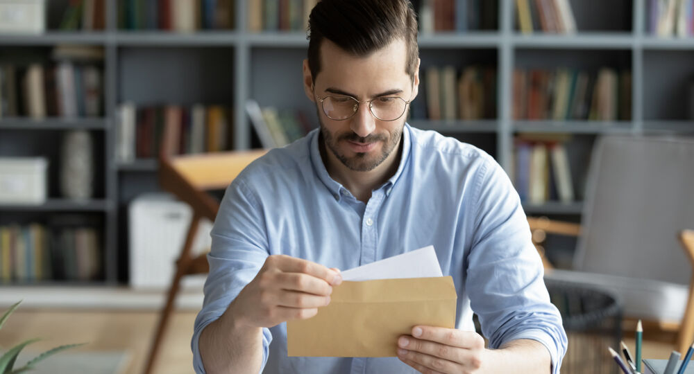 Serious,Businessman,Sit,At,Workplace,Office,Desk,Holding,Envelope,Take