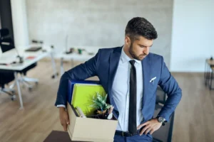 A man is leaving his workplace, holding a box with his belongings.