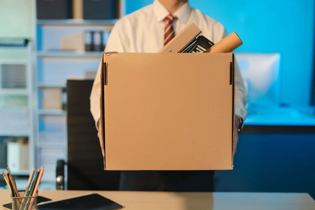 A man is holding a box with his belongings.
