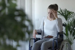 A woman in a wheelchair holding her head