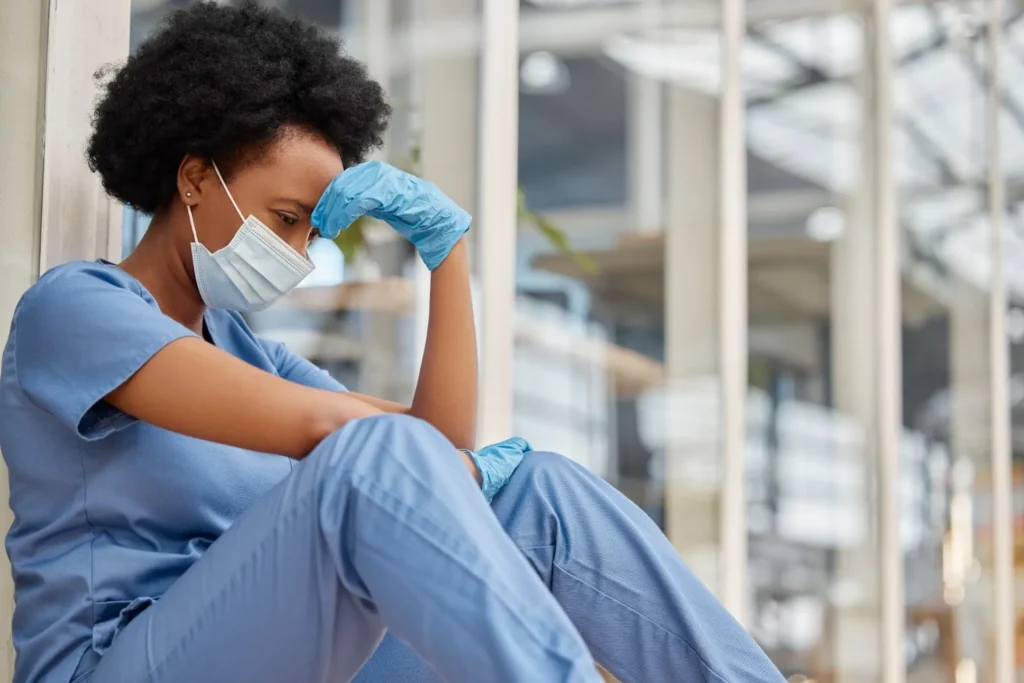 A medical worker sitting and holding his head
